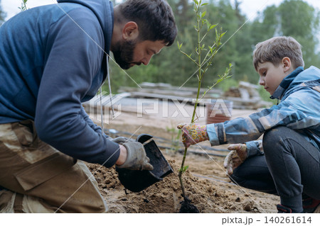 A man and his son plant a dogwood shrub on their countryside property A man and his son plant a dogwood shrub on their countryside property 140261614