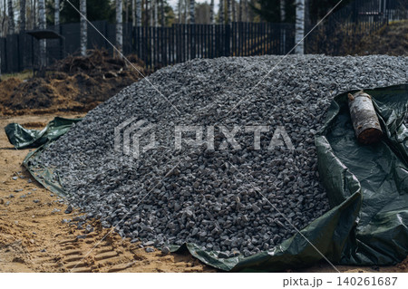 A pile of crushed stone lies on a protective ground cover on a countryside property A pile of crushed stone lies on a protective ground cover on a countryside property 140261687
