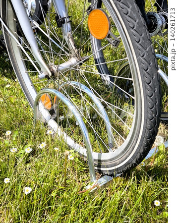 A bicycle wheel in a parking area, amidst green grass and daisies A bicycle wheel in a parking area, amidst green grass and daisies 140261713