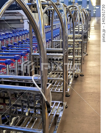 Gleaming chrome luggage carts, neatly lined up in a long row in the airport terminal Gleaming chrome luggage carts, neatly lined up in a long row in the airport terminal 140261730