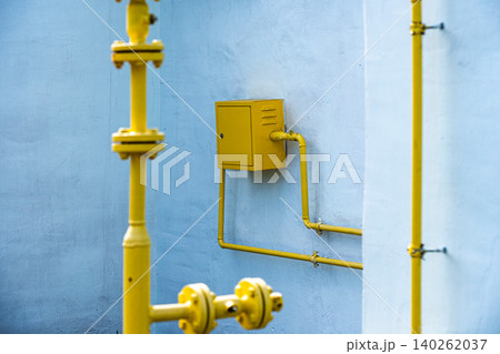 A Vibrant Composition of Yellow Piping and Accessories against a Soft Blue Wall, Showcasing Industrial Design and Color Contrast 140262037