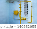 Industrial Pipe Infrastructure: A Close-Up Perspective of Yellow Gas Pipes Against a Light Blue Wall, Highlighting Urban Utility Design and Functionality 140262055