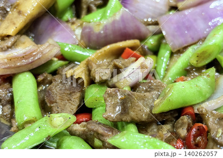 Close up view of stir fried beef strips with green vegetables and red chili pieces served in a savory Asian style preparation Close up view of stir fried beef strips with green vegetables and red chili pieces served in a savory Asian style preparation 140262057