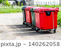 Colorful Trash Bins Lined Up Along a Gravel Path with Lush Green Grass 140262058