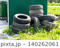Stacked Old Tires Near a Green Shed Surrounded by Grass and Weeds, Highlighting Waste Management and Recycling Challenges in Urban Environments 140262061