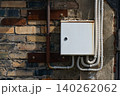 Electrical Junction Box Installed on an Aged Brick Wall Surrounded by Conduits and Metal Fixtures, Showcasing Urban Infrastructure and Maintenance Details 140262062