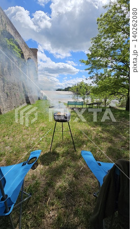 Folding chairs next to barbecue on a sunny day at a picnic by the river 140262080