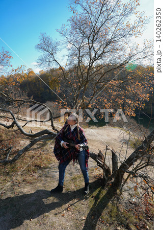 Portrait of smiling caucasian girl plays ukulele in autumnal park. Young woman plays guitar musical instrument outside in nature fall time. Audio music healing 140262350