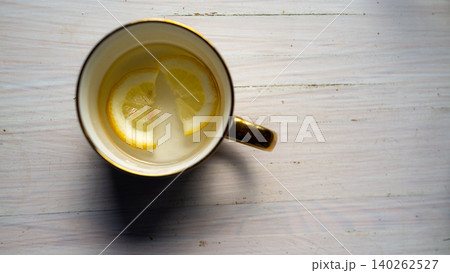 Top view of cup with lemon slices on a white wooden table Top view of cup with lemon slices on a white wooden table 140262527
