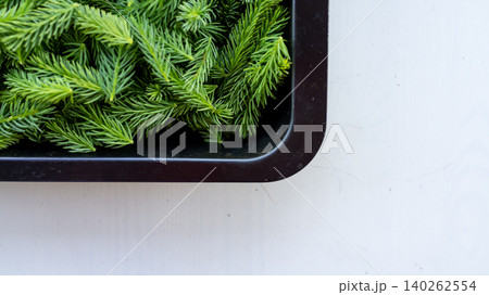 Green pine branches in black tray on white surface 140262554