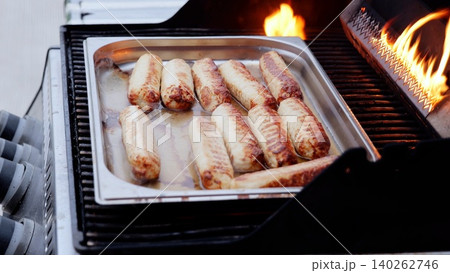 Sizzling bratwurst charring on barbecue grill, flames licking meat, releasing smoky fragrance during backyard summer cookout with friends and family Sizzling bratwurst charring on barbecue grill, flames licking meat, releasing smoky fragrance during backyard summer cookout with friends and family 140262746