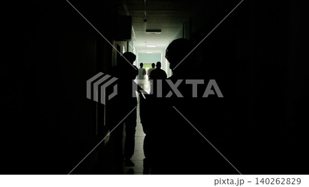 Medical team hurrying through dimly lit hospital hallway, conveying high stakes surgical emergency and professional intensity Medical team hurrying through dimly lit hospital hallway, conveying high stakes surgical emergency and professional intensity 140262829