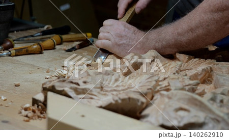 Wood carving process, Craftsman shaping wood delicately, Artisan sculpting floral design from timber diligently, Detailed handwork creating decorative wood panel with tools and skill Wood carving process, Craftsman shaping wood delicately, Artisan sculpting floral design from timber diligently, Detailed handwork creating decorative wood panel with tools and skill 140262910