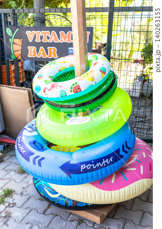 Colorful inflatable pool rings stacked near a vitamin bar sign Colorful inflatable pool rings stacked near a vitamin bar sign 140263155