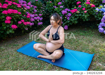 Pregnant woman practicing prenatal yoga in a lotus position, finding tranquility and balance amidst a vibrant garden, promoting health and wellness during pregnancy 140263204