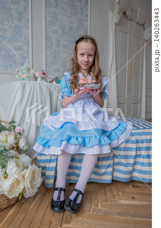 Young Girl In Blue Vintage Dress Holding Doll And Cup, Seated On Striped Bed Near Window, Soft Sunlight, Lace Apron, Ruffled Skirt, Headband, White Stockings, Black Shoes, Bouquet Of Roses On Floor, Young Girl In Blue Vintage Dress Holding Doll And Cup, Seated On Striped Bed Near Window, Soft Sunlight, Lace Apron, Ruffled Skirt, Headband, White Stockings, Black Shoes, Bouquet Of Roses On Floor, 140263443