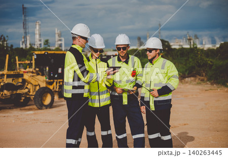 Engineers reviewing plans on tablet at oil and gas refinery site for inspection and management 140263445