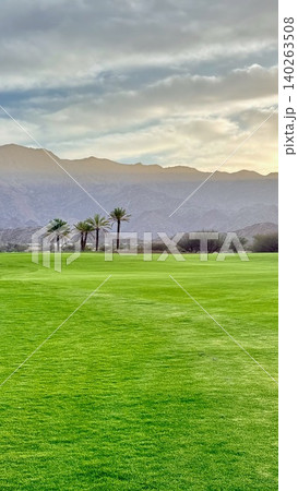 Scenic Panoramic View. Vast Landscape With Dramatic Sky. Open Fairway Surrounded By Mountain Scenery. Expansive Course Bordered By Silhouetted Palms And Distant Mountains Scenic Panoramic View. Vast Landscape With Dramatic Sky. Open Fairway Surrounded By Mountain Scenery. Expansive Course Bordered By Silhouetted Palms And Distant Mountains 140263508