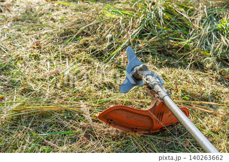 Close-up of grass trimmer on lawn, garden maintenance and lawn care equipment concept Close-up of grass trimmer on lawn, garden maintenance and lawn care equipment concept 140263662