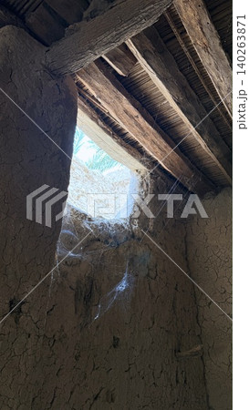 Weathered Ceiling With Sky View. Wooden Beams Expose Sky Behind Weathered Ceiling And Cobwebs. Aged Ceiling Features Webcovered Apertures Revealing Luminous Blue Sky Above Weathered Ceiling With Sky View. Wooden Beams Expose Sky Behind Weathered Ceiling And Cobwebs. Aged Ceiling Features Webcovered Apertures Revealing Luminous Blue Sky Above 140263871