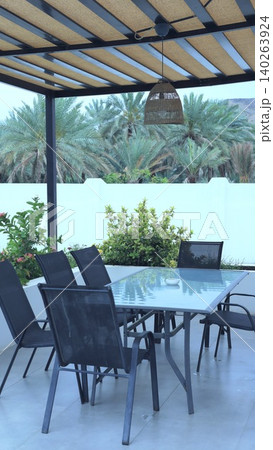 Charming Outdoor Dining. Sunny Shaded Patio Area. Relaxed Outdoor Seating With Lush Surroundings. Inviting Patio Space For Casual Gatherings And Photography Sessions 140263924