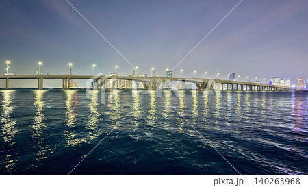 City Night Tranquility. Silent City Bridge With Reflections. Peaceful Urban Scene Illuminated By Gentle Lights. Calm Water Reflecting Glowing Cityscape Under Hazy Sky 140263968