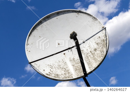 Large parabolic satellite dish antenna structure against bright cloudy sky 140264027