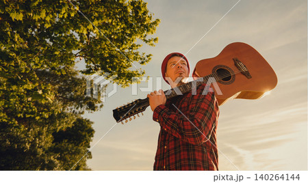 Indie Musician with Acoustic Guitar Outdoors at Sunset Indie Musician with Acoustic Guitar Outdoors at Sunset 140264144