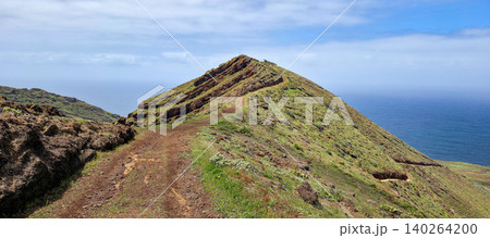Scenic view of a winding dirt path leading up a green hillside overlooking the ocean in a coastal landscape. Northern viewpoint of La Palma Island Cruz de La Centinela. High quality photo Scenic view of a winding dirt path leading up a green hillside overlooking the ocean in a coastal landscape. Northern viewpoint of La Palma Island Cruz de La Centinela. High quality photo 140264200