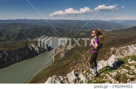 Female Explorer with Backpack Standing on Mountain Looking at Horizon Female Explorer with Backpack Standing on Mountain Looking at Horizon 140264403