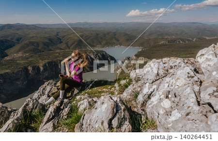 Woman Hiker Sitting on Mountain Peak Drinking Water Woman Hiker Sitting on Mountain Peak Drinking Water 140264451