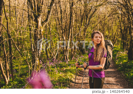 Woman Trekking on Forest Path with Purple Wildflowers Woman Trekking on Forest Path with Purple Wildflowers 140264540