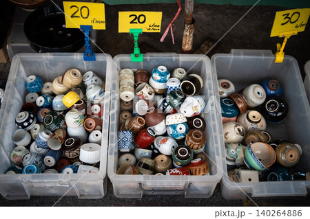 Containers filled with different cheap ceramic pots made from old used mugs selling at flower market 140264886