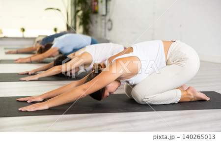 Group of women relaxing in Child Pose Balasana during yoga training in gym Group of women relaxing in Child Pose Balasana during yoga training in gym 140265013