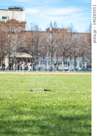 Special irrigation system evenly sprays water across fresh green lawn in park, seasonal landscaping. Special irrigation system evenly sprays water across fresh green lawn in park, seasonal landscaping. 140265051
