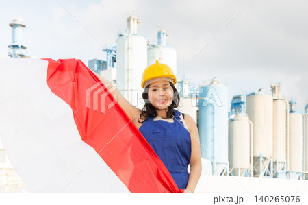 National flag of Indonesia in the hands of girl in overalls against background of modern metallurgical plant National flag of Indonesia in the hands of girl in overalls against background of modern metallurgical plant 140265076
