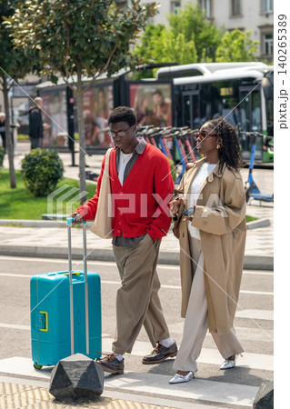 Stylish african american married couple man and woman walking on street with suitcase to hotel. Stylish african american married couple man and woman walking on street with suitcase to hotel. 140265389