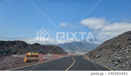 A new road laid through solidified lava flows after the eruption of the Tajogaite volcano on La Palma Island and ongoing repair and construction work and extraction of volcanic stones near the road A new road laid through solidified lava flows after the eruption of the Tajogaite volcano on La Palma Island and ongoing repair and construction work and extraction of volcanic stones near the road 140265441
