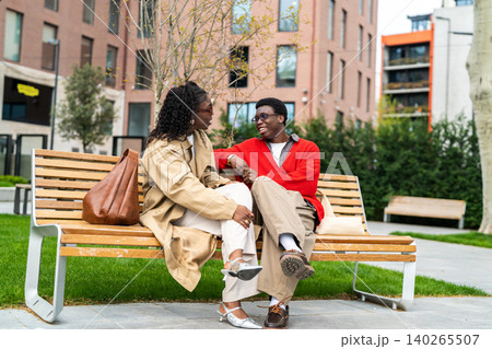Positive african american couple man and woman sitting in city enjoying relationship communications. Positive african american couple man and woman sitting in city enjoying relationship communications. 140265507