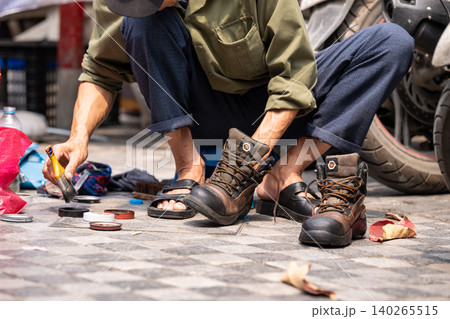 Local man cleaning shoes for locals and tourists, popular cheap street service in Hanoi, Vietnam. Local man cleaning shoes for locals and tourists, popular cheap street service in Hanoi, Vietnam. 140265515