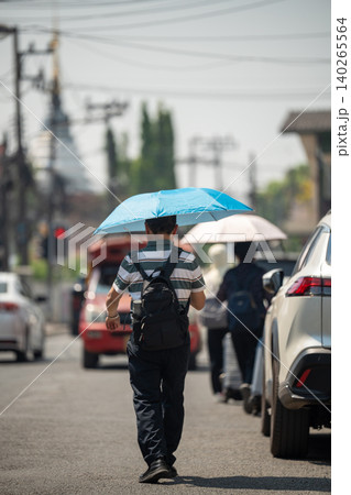 Man walking through city holding umbrella, health safety and protection from heatstroke in heatwave. Man walking through city holding umbrella, health safety and protection from heatstroke in heatwave. 140265564