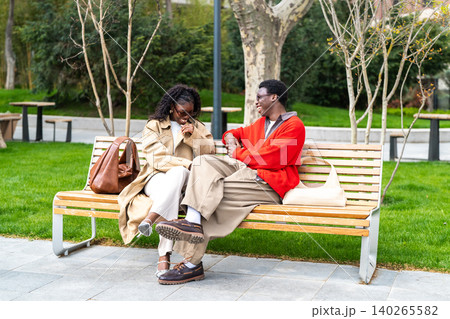 Joyful african american couple man and woman on daily walk together sitting joking and smiling. 140265582