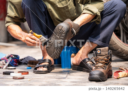 Local man cleaning shoes for locals and tourists, popular cheap street service in Hanoi, Vietnam. 140265642