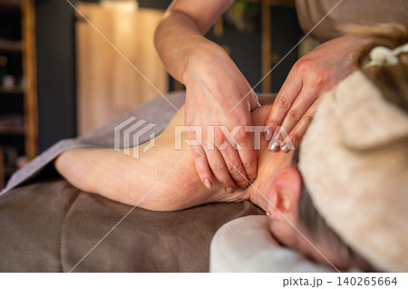 Woman lying on spa bed in salon receiving relaxation massage treatment from professional masseur. Woman lying on spa bed in salon receiving relaxation massage treatment from professional masseur. 140265664
