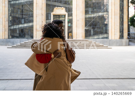 Fashionable African american man and woman friends meeting together at city street and hugging. Fashionable African american man and woman friends meeting together at city street and hugging. 140265669