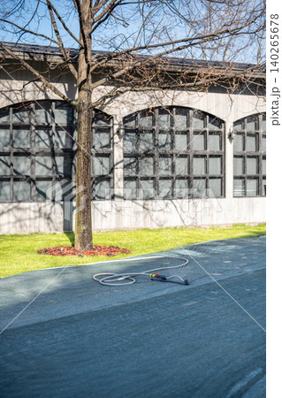 Grass lawn preparations for summer season in public city areas, workers covering turf with netting. 140265678