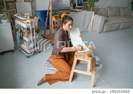 Creative working process at home gallery, thoughtful woman artist makes watercolor sketches in album 140265689
