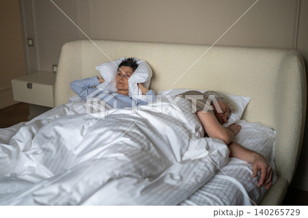 Elderly husband sleeping and snoring loudly at night causing discomfort and frustration to wife. Elderly husband sleeping and snoring loudly at night causing discomfort and frustration to wife. 140265729