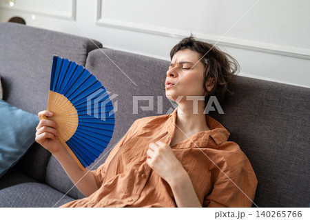 Tired woman distressed from overheating and dizziness lying on sofa suffering from summer weather. 140265766