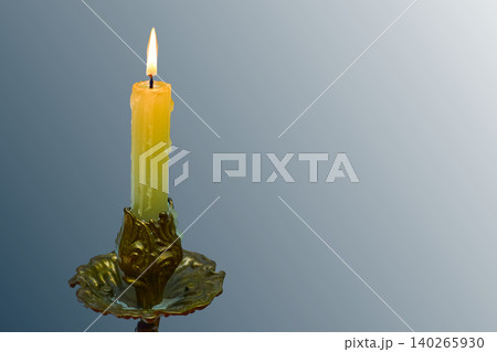 Burning candle in bronze candlestick on silver blue gray 140265930